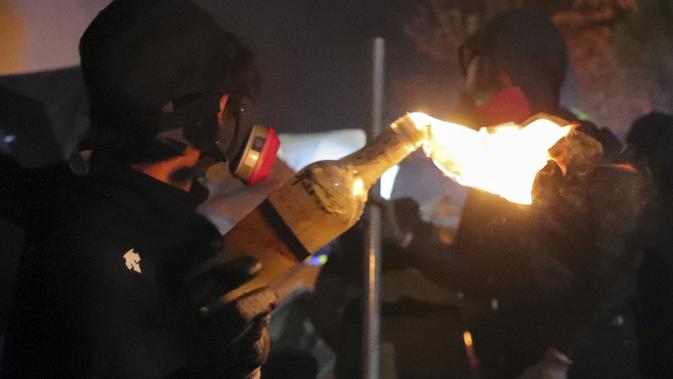 Seorang siswa memegang bom molotov selama bentrokan di Universitas Cina di Hong Kong (12/11/2019). Gerakan antipemerintah Hong Kong yang telah berlangsung selama lima bulan bertindak semakin keras. (AP Photo/Kin Cheung)
