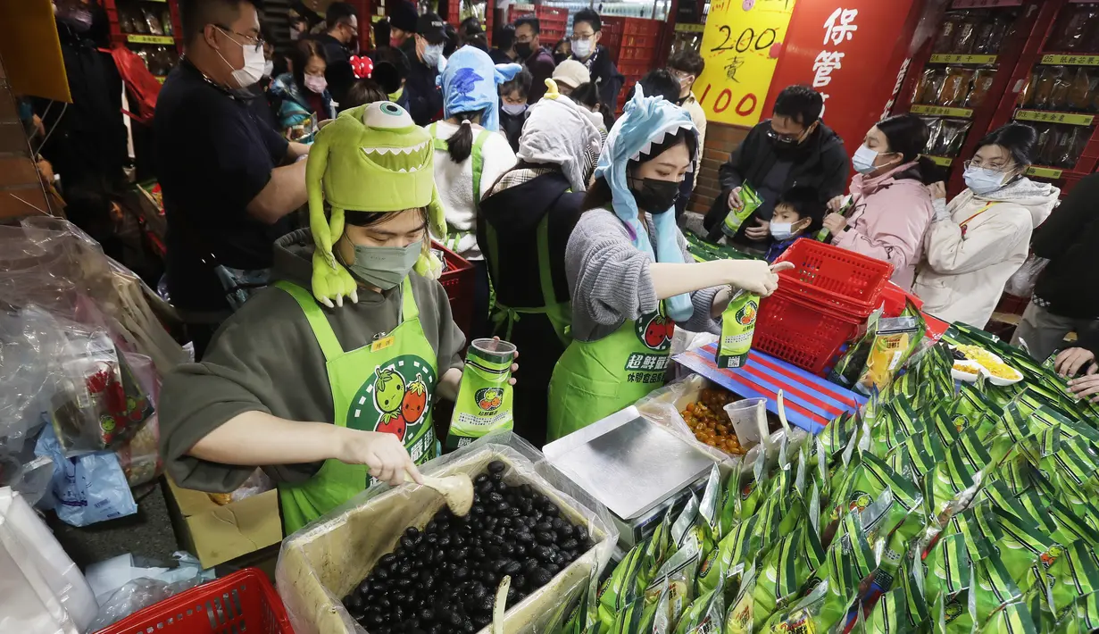 Pekerja toko mengemas barang saat pengunjung berbelanja untuk perayaan Tahun Baru Imlek mendatang di pasar Jalan Dihua di Taipei, Taiwan, Jumat, 20 Januari 2023. Pembeli Taiwan mulai berburu makanan lezat, jajanan kering, dan barang murah lainnya di pasar menjelang perayaan Tahun Baru Imlek yang menurut kalender lunar akan berlangsung pada 22 Januari. (AP Photo/Chiang Ying-ying)