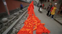 Seorang wanita mengenakan kostum dari plastik berbentuk kerucut selama protes yang dilakukannya di Beijing, Cina, (7/12). Ia menamakan karya kostumnya ini dengan judul "The Orange Horns Bride Marries the Blue Sky". (REUTERS/Damir Sagolj)