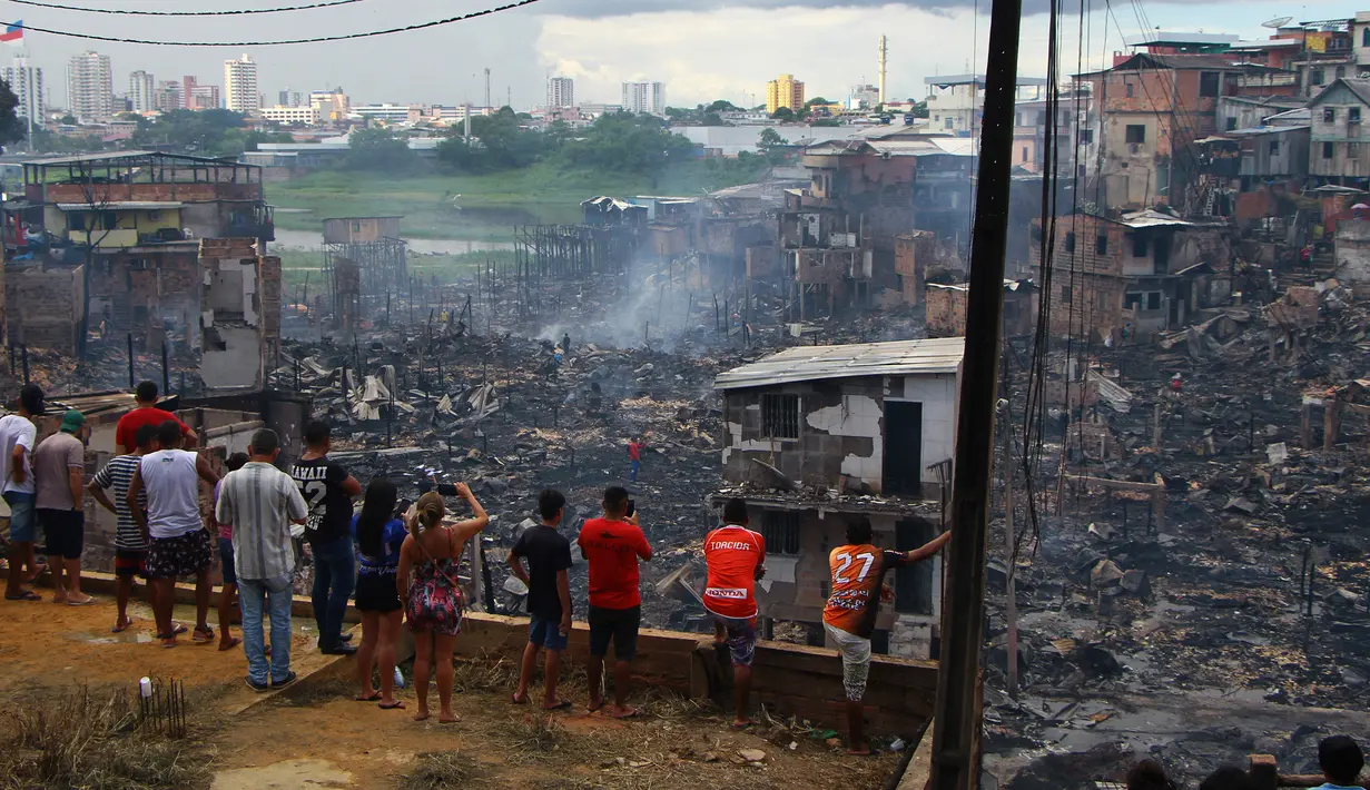 Sejumlah warga melihat sisa-sisa rumah yang hangus di lingkungan Educandos di Manaus, Brasil (17/12). Para pihak berwenang mengatakan setidaknya 600 rumah kayu hanggus terbakar. (AP Photo/Edmar Barros)