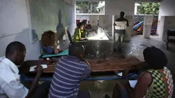 Petugas pemilu menunjukan gambar surat suara saat berlangsungnya pemilu  di Port-au-Prince, Haiti (20/11). Pemilihan umum ini sempat tertunda pada bulan Oktober lalu akibat badai Matthew yang melanda Haiti. (Reuters/Jeanty Junior Augustin) 