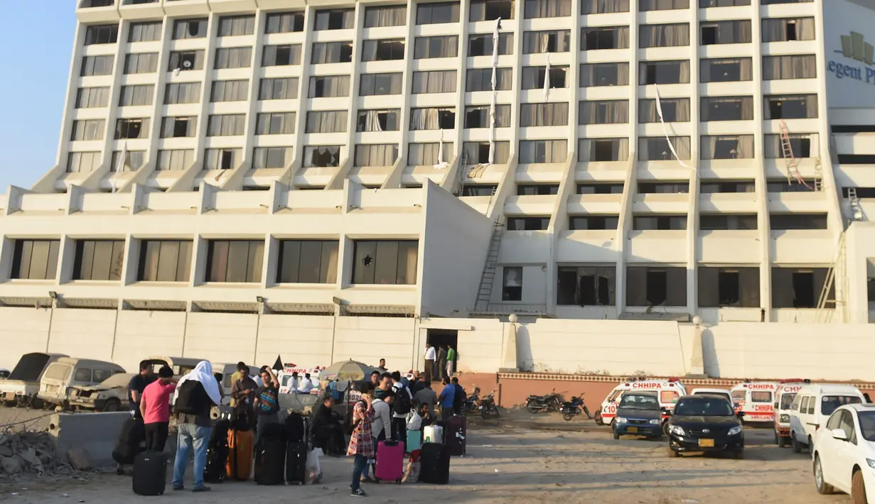 Para tamu berkumpul di luar sebuah hotel mewah yang mengalami kebakaran di kota Karachi, Pakistan, Senin (5/12). Sedikitnya 11 orang tewas dan puluhan lainnya luka-luka akibat musibah tersebut. (RIZWAN Tabassum/AFP)