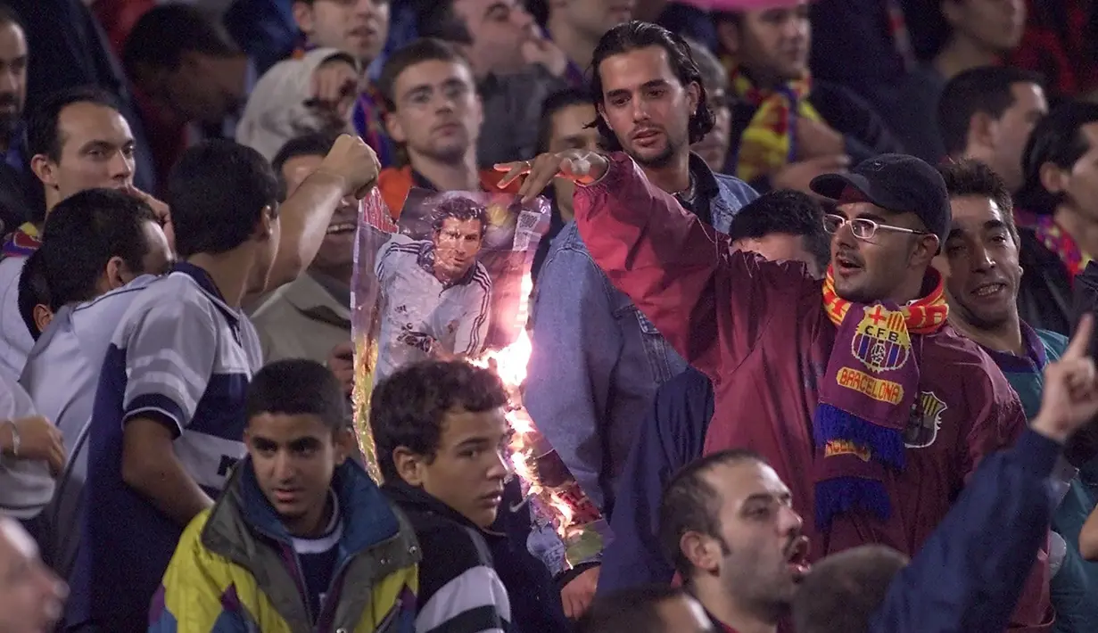 Kala Real Madrid bertandang ke markas Barcelona saat El Clasico musim 2002/2003. Beberapa kelompok suporter Barcelona membakar poster Figo dan melakukan aksi pelemparan ke dalam stadion ketika Figo hendak melakukan sepak pojok. (AFP/Christophe Simon)