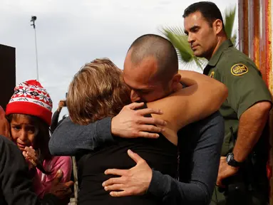 Seorang pria memeluk keluarganya di depan gerbang perbatasan Meksiko dan Amerika Serikat, Tijuana, Meksiko (19/11). Untuk memperingati Hari Anak Sedunia, petugas perbatasan membolehkan imigran Meksiko bertemu dengan keluarganya. (Reuters/Jorge Duenes)