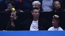 Pemain Juventus, Cristiano Ronaldo menangkap bola tenis yang mengarah kepadanya dan sang kekasih, Georgina saat menyaksikan Novak Djokovic menghadapi John Isner pada laga tenis dunia, ATP Finals 2018, di O2 Arena, London, Senin (12/11). (Glyn KIRK/AFP)