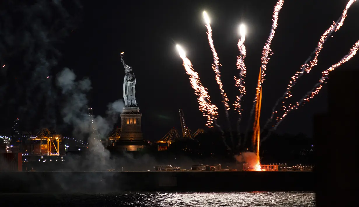 Kembang api yang diluncurkan dari tongkang meledak di atas Pelabuhan New York dan Patung Liberty di New York, Selasa (15/6/2021). Kembang api yang menandai berakhirnya pembatasan COVID-19 di seluruh negara bagian tersebut untuk menghormati para kelompok pekerja penting. (AP Photo/Craig Ruttle)