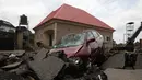 Sebuah mobil terlihat di jalan yang terkena banjir bandang setelah hujan deras di Trademoore Estate, Lugbe, Abuja, Nigeria (13/9/2021). Badan Manajemen Darurat Nasional Nigeria (NEMA) mengkonfirmasi 3 orang tewas, dan puluhan mobil dan rumah terkena dampak di malapetaka. (AFP/Kola Sulaimon)