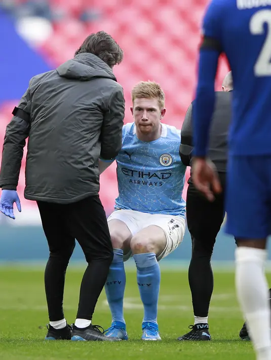 Gelandang Manchester City, Kevin De Bruyne berdiri dibantu oleh staf medis setelah mengalami cedera saat bertanding melawan Chelsea pada pertandingan semifinal Piala FA di Stadion Wembley di London, Inggris, Minggu (18/4/2021). Chelsea menang tipis atas City 1-0. (AP Photo/Ian Walton, Pool)
