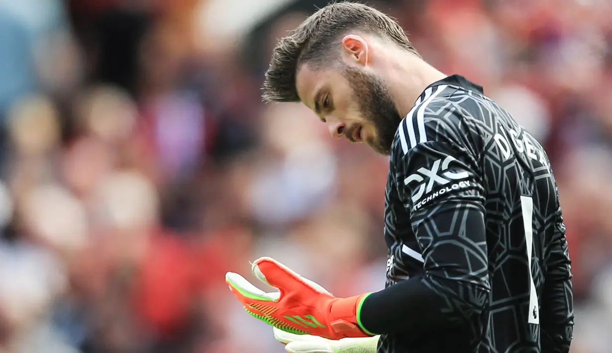 Kiper Manchester United, David de Gea, mengamati kedua tangannya saat melawan Brighton and Hove Albion pada laga Liga Inggris di Stadion Old Trafford, Minggu (07/08/2022). (AP/Lindsey Parnaby)