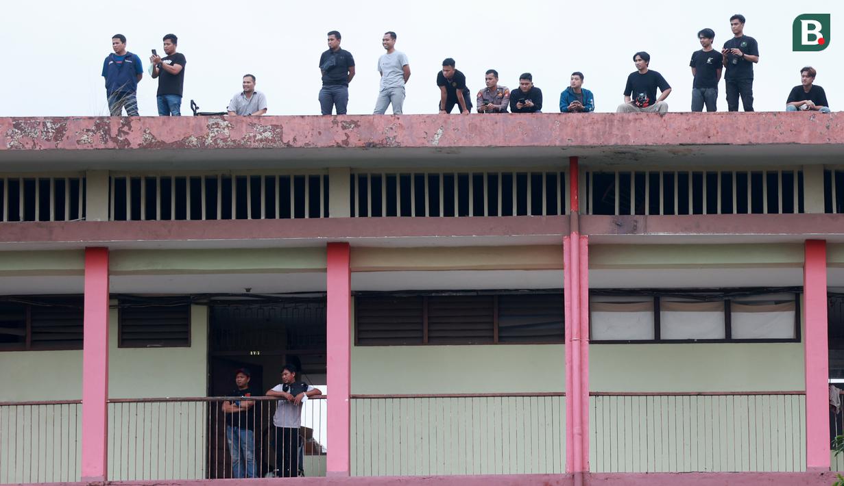 Penonton menyaksikan pertandingan antara Arema FC melawan PSM Makassar dari atap asrama Kepolisan pada laga BRI Liga 1 di Stadion PTIK, Jakarta, Sabtu (4/2/2023). PSM Makassar menang dengan skor 1-0. (Bola.com/M Iqbal Ichsan)