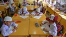 Dengan seragam lengkap, anak-anak sudah melakukan pembelajaran dengan menggunakan peralatan sekolah yang mereka bawa. (Chaideer MAHYUDDIN/AFP)