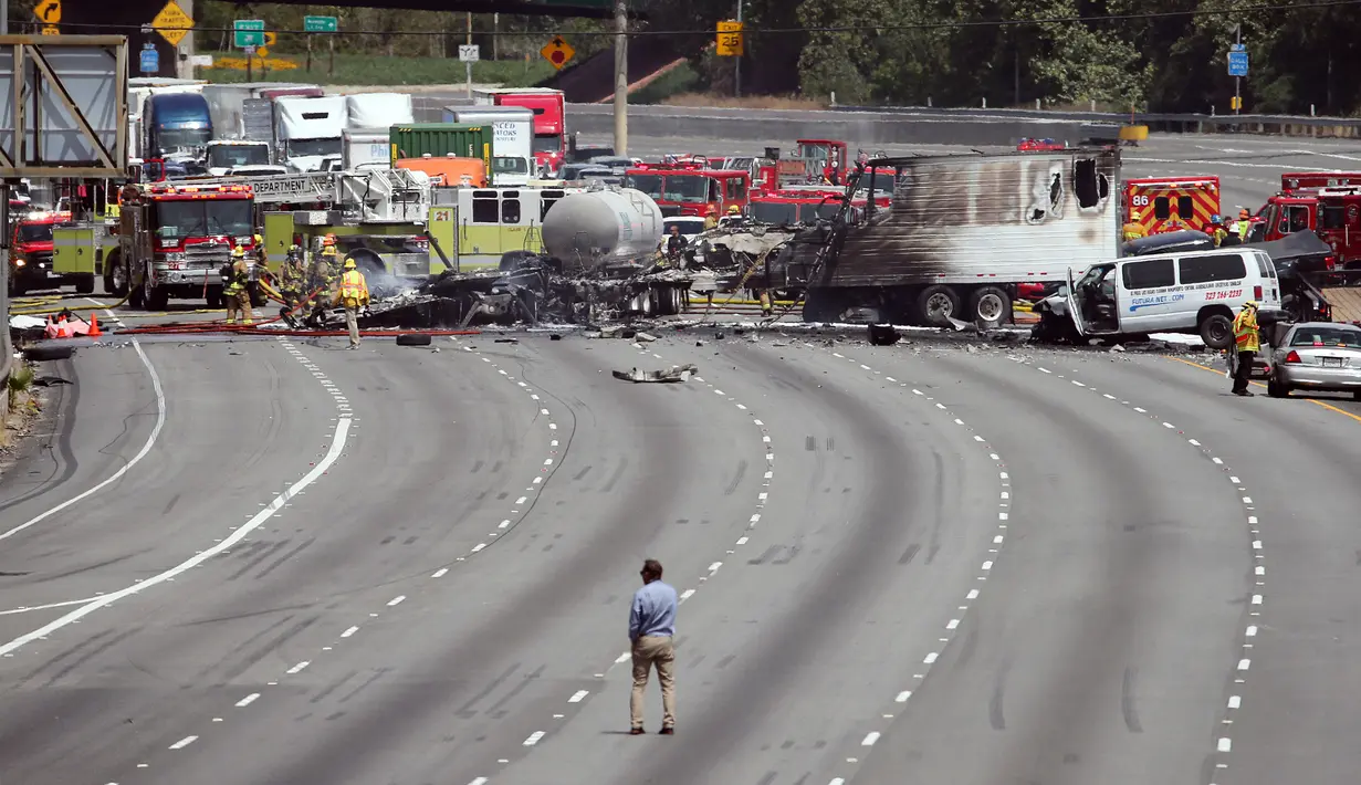 Penyidik memeriksa bangkai truk yang telah hangus usai terjadi tabrakan antara dua truk besar di utara pusat kota Los Angeles (25/4). Kecelakaan ini menewaskan satu orang dan melukai sejumlah orang lainnya. (AP Photo/Reed Saxon)