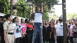 Petugas Polisi Punjab menyaksikan seorang wanita muda melakukan pull-up selama sesi pelatihan untuk bergabung dengan Polisi Punjab di Amritsar, India, Senin (28/6/ 2021). (AFP/Narider Nanu)
