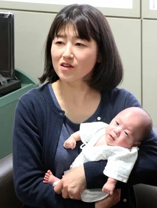 Ryusuke Sekino, bayi laki-laki terkecil di dunia digendong oleh ibunya Toshiko Sekino di sebuah rumah sakit di Azumino, Prefektur Nagano, Jepang, Jumat (19/4). Bayi yang lahir pada 1 Oktober 2018 tersebut kini telah mencapai 3,3 kiliogram berkat perawatan dokter. (Kyodo News via AP)