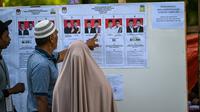 Melalui Pilkada, para pemimpin daerah yang dipilih langsung oleh rakyat diharapkan bekerja lebih maksimal dalam menjalankan tugas dan meningkatkan kesejahteraan masyarakat. Tampak dalam foto, calon pemilih memeriksa kandidat sebelum memberikan suara mereka dalam pemilihan eksekutif lokal di Darul Imarah, pinggiran Banda Aceh pada 27 November 2024. (CHAIDEER MAHYUDDIN/AFP)