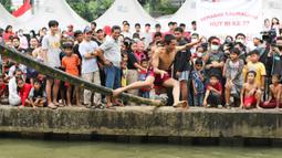 Seorang warga terjatuh saat mengikuti perlombaan jalan di atas bambu di aliran Kalimalang, Jakarta Timur, Sabtu (27/8/2022). Perlombaan di Kalimalang yang diselenggarakan kembali setelah dua tahun berhenti akibat pandemi covid-19 ini untuk memeriahkan peringatan HUT ke-77 Kemerdekaan RI. (Liputan6.com/Herman Zakharia)