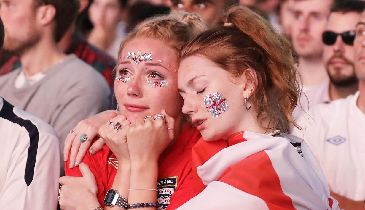 Dua orang fans tampak sedih usai timnas Inggris gagal melaju ke final Piala Dunia di Hyde Park, London, Rabu (11/7/2018). Kroasia menang 2-1 atas Inggris. (AP/Matt Dunham)