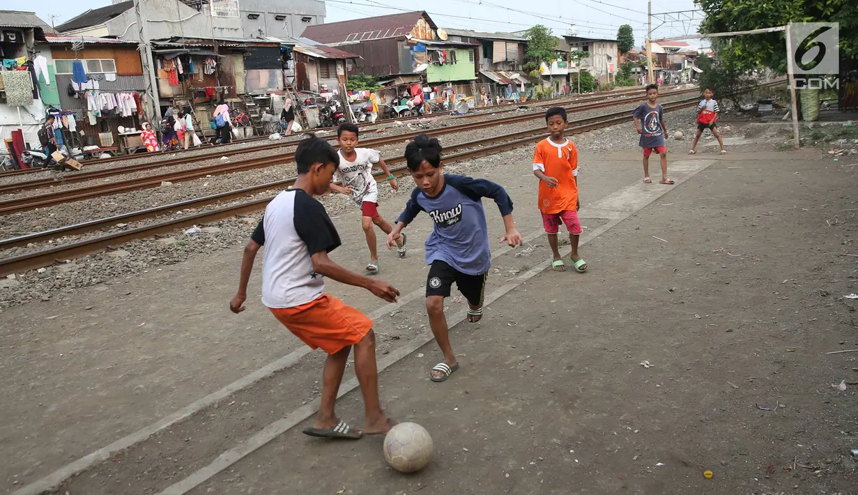 Anak-anak bermain sepak bola di pinggir rel kereta api di kawasan Kemayoran, Jakarta, Senin (24/7). Minimnya lahan bermain menyebabkan anak-anak terpaksa bermain di lokasi tersebut, meskipun berbahaya bagi keselamatan. (Liputan6.com/Immanuel Antonius)