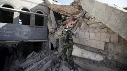 Militan Houthi melihat reruntuhan bangunan Perdagangan dan Industri yang hancur di Sanaa, Yaman, (5/1). Koalisi yang dipimpin Arab Saudi intensifkan serangan udara ke Yaman, Targetnya milisi Syiah Houthi yang didukung Iran. (REUTERS / Khaled Abdullah)