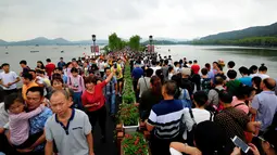 Pengunjung menunggu hantaman gelombang di tepi Sungai Qiantang di Hangzhou, provinsi Zhejiang, Tiongkok, 4 Oktober 2016. Hantaman gelombang ini menjadi daya tarik tersendiri bagi wisatawan. (REUTERS)