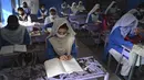 Siswa yang mengenakan masker menghadiri kelas di sebuah sekolah di Lahore (16/9/2021). Pemerintah Pakistan membuka kembali lembaga pendidikan yang ditutup sebagai tindakan pencegahan untuk mengekang penyebaran virus corona Covid-19. (AFP/Arif Ali)