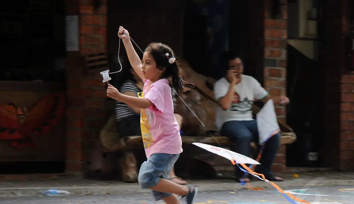 Sambil berlari, salah satu anak mencoba menerbangkan layang-layang buatannya di Museum Layang-Layang, Jakarta, (27/9/2014). (Liputan6.com/Helmi Fithriansyah)
