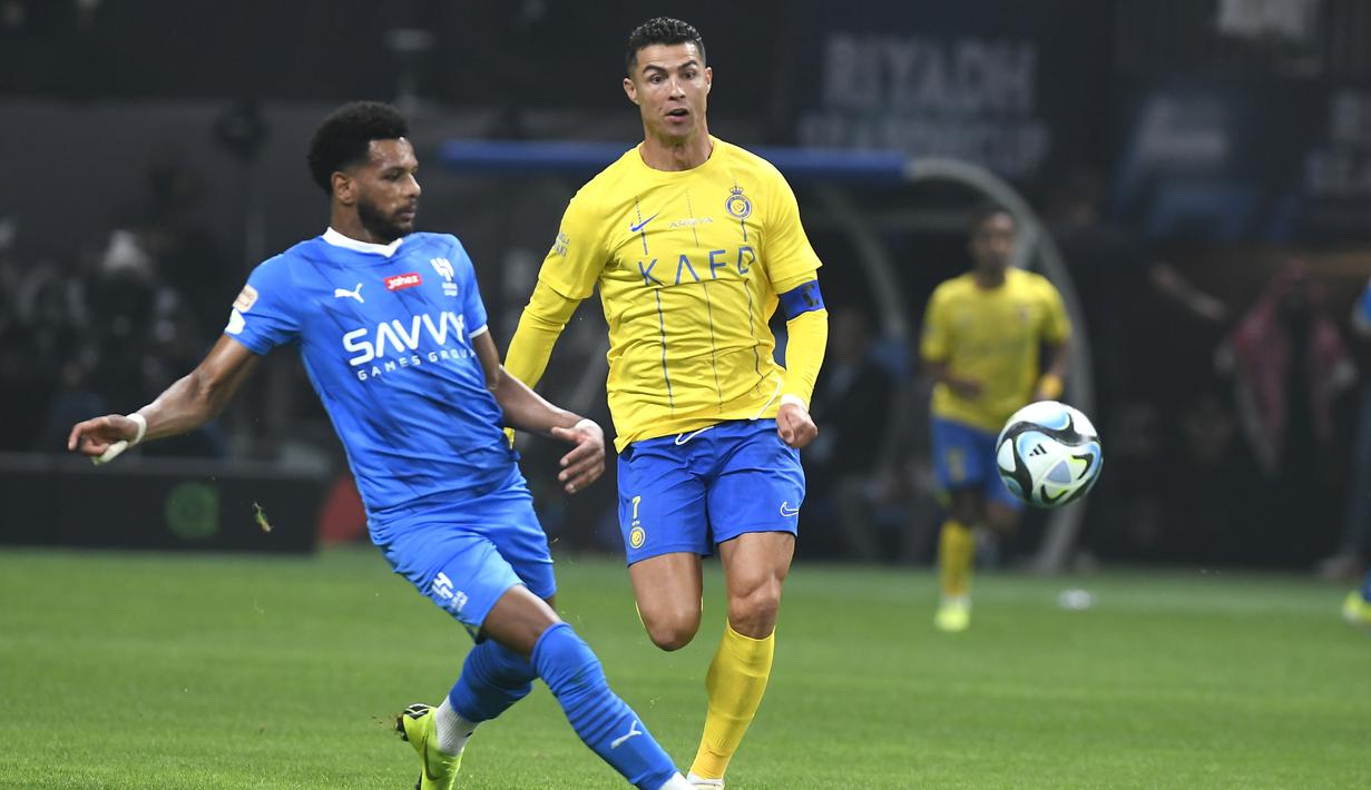 Pemain Al-Nassr, Cristiano Ronaldo, berebut bola dengan pemain Al-Hilal, Al Bulayhi, pada laga persahabatan di Kingdom Arena, Riyadh, Jumat (9/2/2024). (AP Photo)