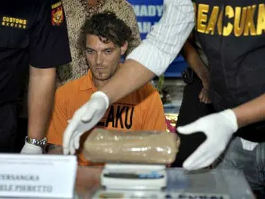 Petugas Bea Cukai memeriksa barang bukti hashis di hadapan tersangka warga Italia, Daniele Pieretto (tengah) saat gelar kasus penyelundupan narkoba di Kantor Bea Cukai Bandara Ngurah Rai, Bali, Sabtu (31/3). Tersangka berupaya menyelundupkan 1,430 Kg hashis dengan menyembunyikannya di dinding tas bawaannya. (Antara)