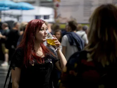 Seorang wanita menikmati minum bir selama The Great British Beer Festival di Kensington Olympia di London barat (6/8/2019). Great British Beer Festival tahunan ini diadakan 6-10 Agustus 2019. (AFP Photo/Tolga Akmen)