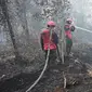 Petugas pemadam kebakaran berupaya melakukan pemadaman di tengah pekatnya asap kebakaran di Kampar, provinsi Riau pada 17 September 2019. Kebakaran hutan dan lahan (karhutla) yang masih terjadi membuat sejumlah wilayah di Provinsi Riau terpapar kabut asap. (ADEK BERRY / AFP)
