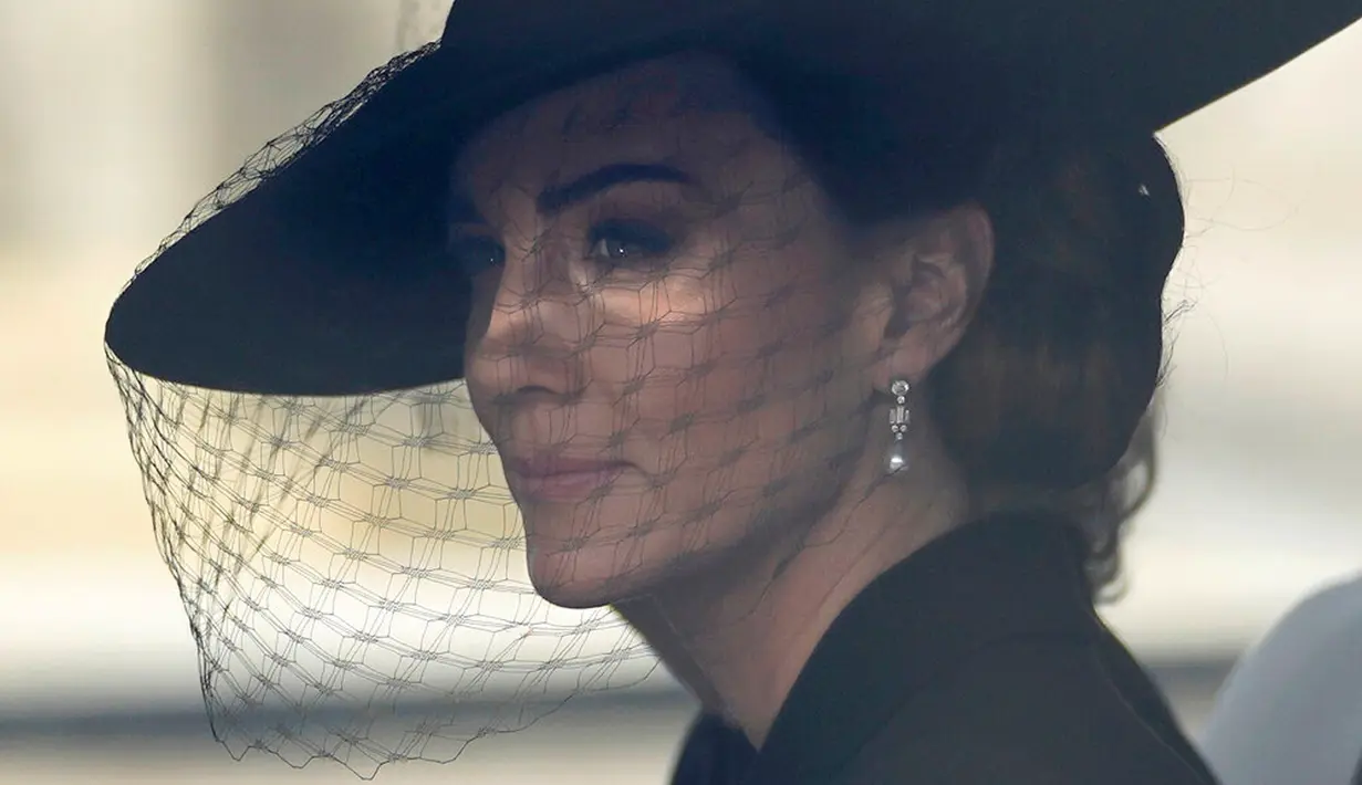 Putri Wales Kate Middleton duduk dalam mobil saat prosesi pemakaman Ratu Elizabeth II di London, Inggris, 19 September 2022. Sama seperti kerabat lainnya, Kate hadir dengan pakaian serba hitam. (AP Photo/Markus Schreiber, Pool)