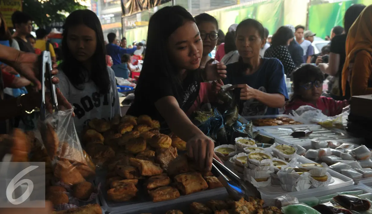 Pembeli mengambil sendiri kue yang dijajakan di Pasar Takjil Benhil, Jakarta, Senin (6/6). Harga yang relatif murah menjadikan pasar ini kerap ramai selama Ramadan. (Liputan6.com/Gempur M Surya)