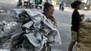 Seorang ibu bersama anaknya mengumpulkan koran yang digunakan sebagai alas, Jatinegara, Jakarta, Rabu (6/7/2016). Usai ribuan warga menunaikan salat Id, tumpukan koran berserakan dimana-mana. (Liputan6.com/Yoppy Renato)