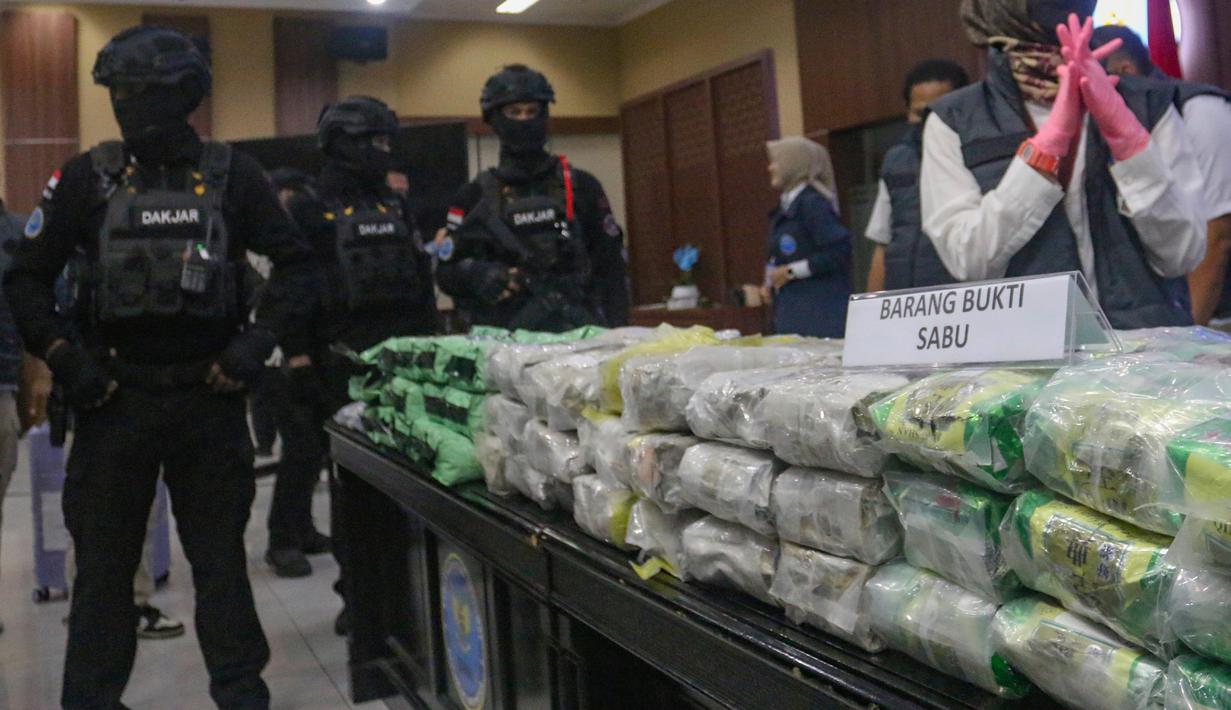 Petugas Badan Narkotika Nasional (BNN) menjaga barang bukti narkotika saat pengungkapan hasil Operasi Saber Bersinar 2026 di Kantor BNN RI, Jakarta, Selasa (19/05/2026). (merdeka.com/Arie Basuki)