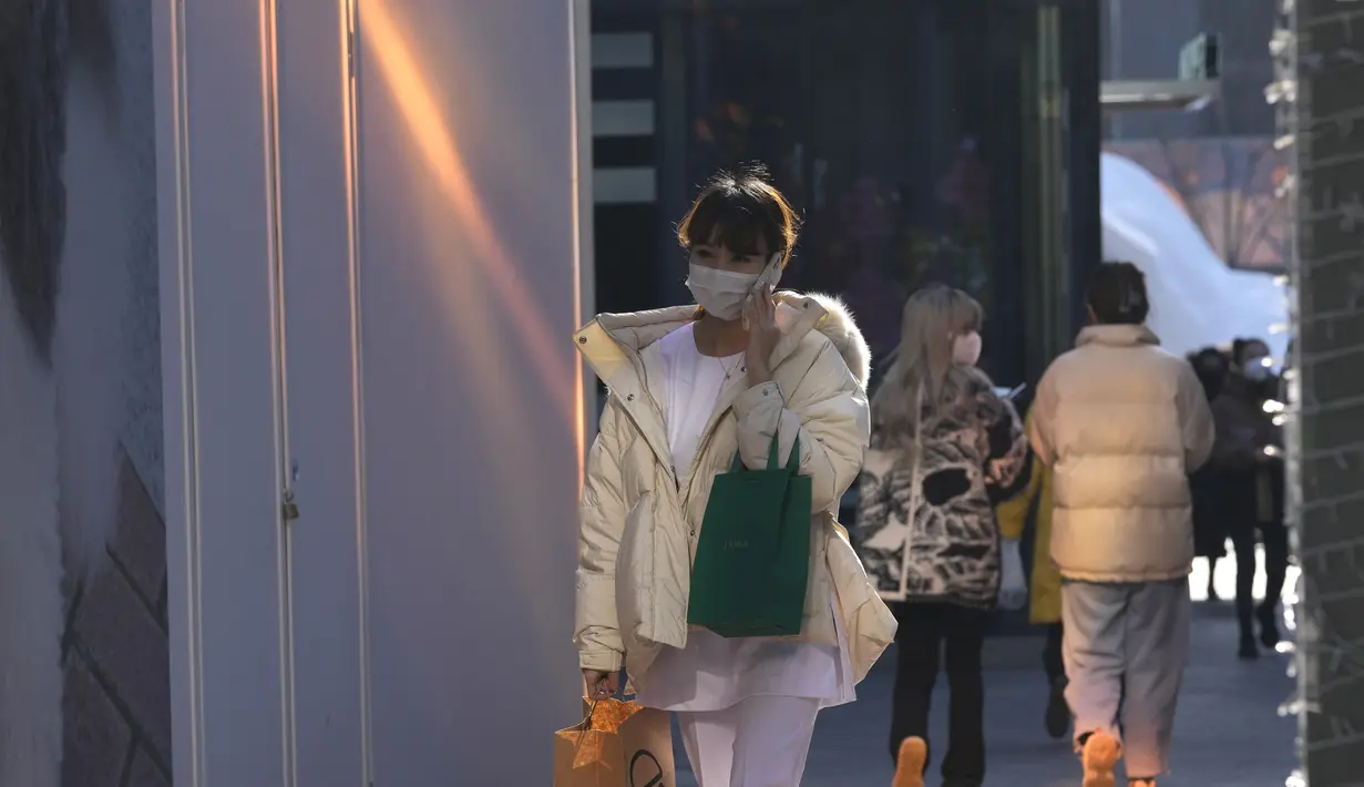 Seorang wanita memakai masker saat mengunjungi pusat perbelanjaan di Beijing, China, Selasa (14/12/2021). Kasus pertama varian omicron COVID-19 telah terdeteksi di daratan negara di kota Tianjin di sebelah timur Beijing. (AP Photo/Ng Han Guan)