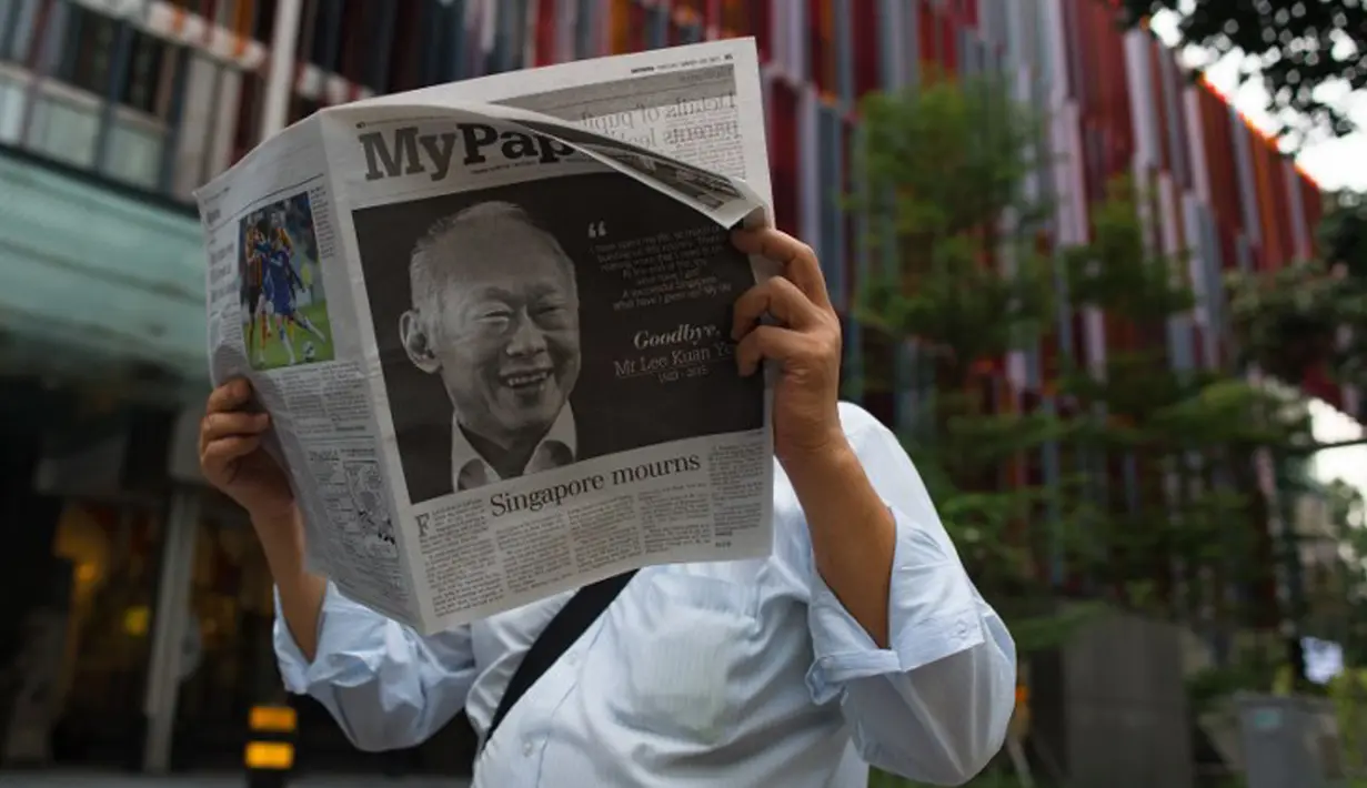 Seorang pria membaca koran setelah sehari meninggalnya mantan PM Singapura, Lee Kuan Yew, Singapura, Selasa (24/3/2015). Lee meninggal pada hari Senin (23/3) di usia 91 tahun dan wajahnya menghiasi berbagai media cetak Singapura. (AFP PHOTO/Mohd RASFAN)