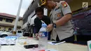 Petugas mengecek barang bukti narkoba saat menggelar perkara kasus pengedaran narkoba jenis shabu dan psikotopika golongan IV serta obat daftar G pada sebuah sekolah di Jakarta, Selasa (15/1). (Merdeka.com/Imam Buhori)