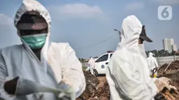 Petugas mengenakan baju hazmat saat memakamkan jenazah pasien Covid-19 di TPU Rorotan, Jakarta, Minggu (28/3/2021). Hingga hari ini sudah ada 9 jenazah pasien Covid-19 dimakamkan di TPU Rorotan yang berkapasitas 1.500 petak makam tersebut. (merdeka.com/Iqbal S. Nugroho)