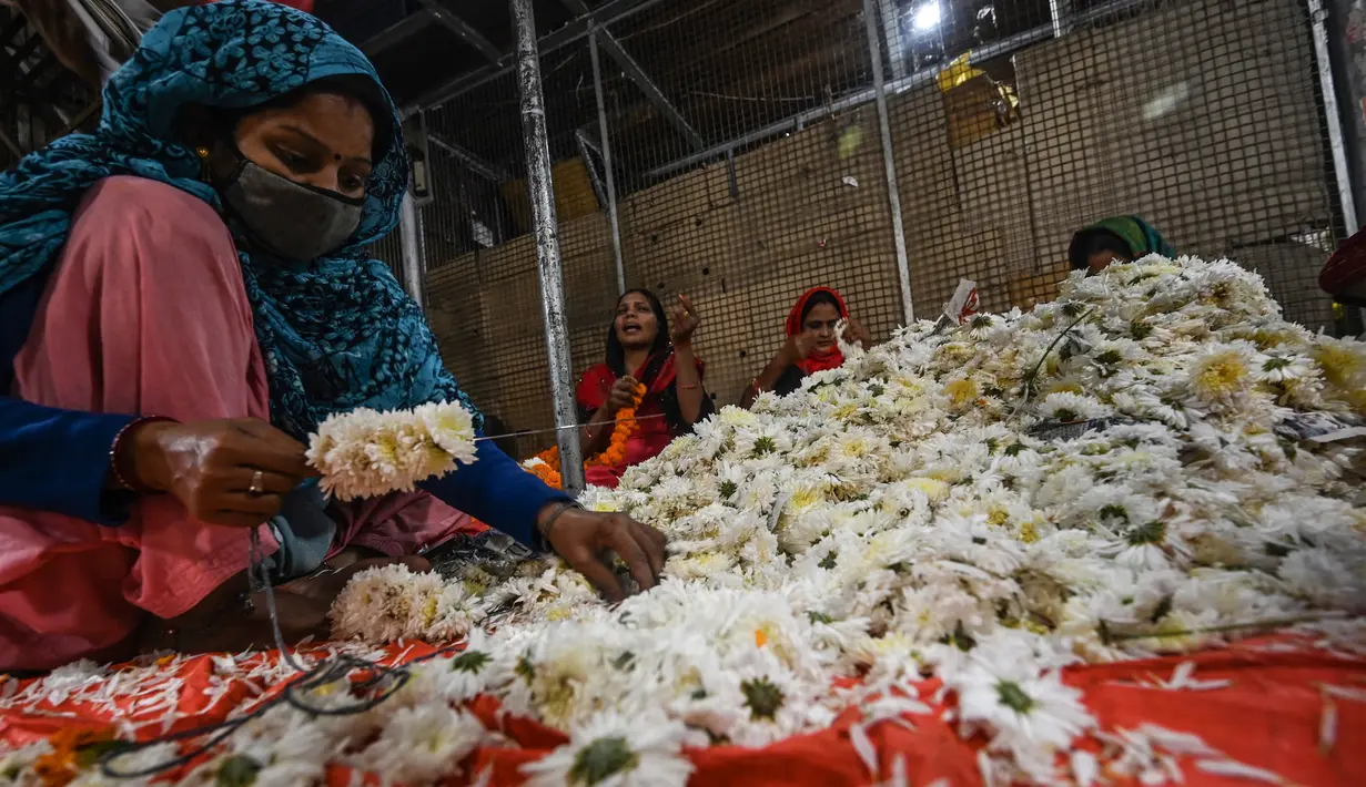 Seorang wanita membuat karangan bunga jelang Festival Diwali di pasar bunga New Delhi, India, Minggu (31/10/2021). Festival Diwali atau Festival Cahaya dalam agama Hindu melambangkan kemenangan baik atas buruk. (Money SHARMA/AFP)