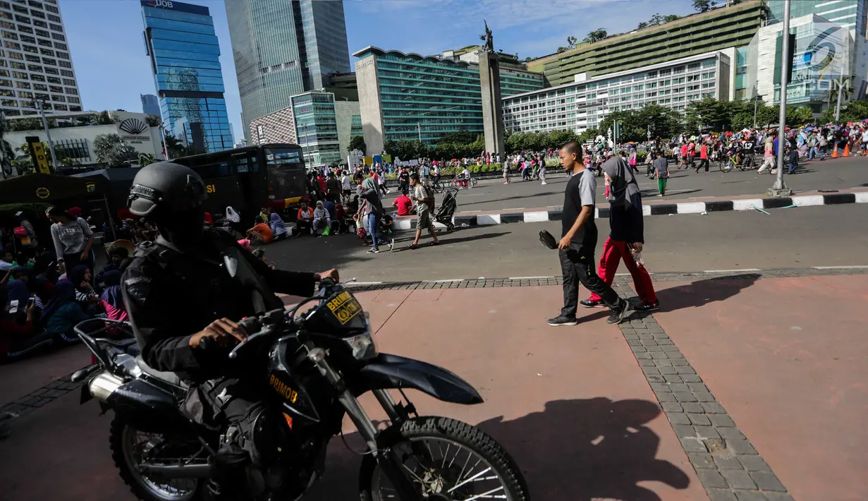 Pasukan Brimob mengendarai motor dan bersenjata lengkap berpatroli saat Car Free Day di kawasan Bunderan HI, Jakarta, Minggu (24/12). Operasi Lilin 2017 ini guna memberikan kenyamanan pada masyarakat. (Liputan6.com/Faizal Fanani)