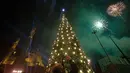 Warga mengambil gambar pohon natal yang sedang dihiasi percikan kembang api di dekat Masjid Mohammad al-Amin di Beirut, Lebanon (10/12). (AFP Photo/Stringer)