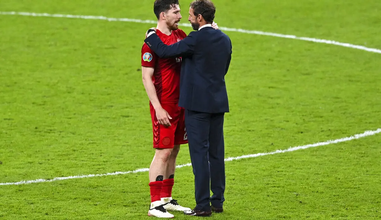 Pelatih Inggris, Gareth Southgate menghibur pemain Denmark Pierre Hojbjerg setelah Inggris mengalahkan Denmark di semifinal Euro 2020 di stadion Wembley di London, Kamis (8/7/2021). Inggris menang atas Denmark dengan skor 2-1. (Justin Tallis/Pool Photo via AP)