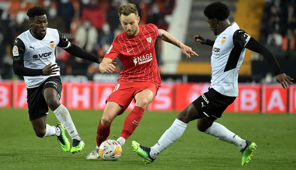 Gelandang Sevilla, Ivan Rakitic (tengah) berusaha melewati pemain Valencia, Yunus Musah dan Thierry Correia selama pertandingan lanjutan La Liga Spanyol di stadion Mestalla di Valencia (20/1/2022). Valencia bermain imbang atas Sevilla 1-1. (AFP/Jose Jordan)