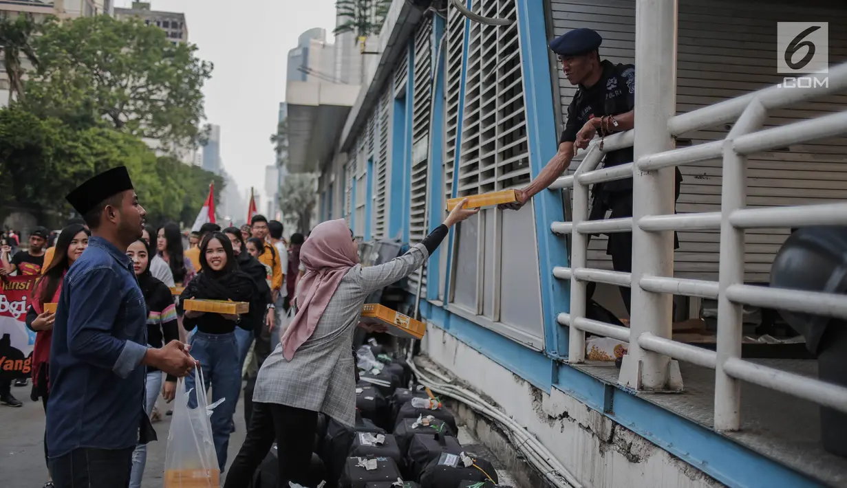 Peserta aksi yang tergabung dalam Mahasiswa dan Pemuda Relawan Cinta NKRI membagikan takjil ke anggota Polri yang bertugas di Gedung Bawaslu RI, Jakarta, Minggu (26/5). Aksi simpatik sebagai wujud apresiasi kepada anggota Polri-TNI yang menjaga keamanan aksi 22 Mei 2019. (Liputan6.com/Faizal Fanani)