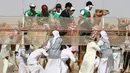 Asisten joki membantu mempersiapkan unta saat balapan unta di festival warisan Sheikh Sultan Bin Zayed al-Nahyan di Abu Dhabi, Uni Emirat Arab (10/2). Balap unta merupakan olahraga tradisional dari Uni Arab Emirates. (AFP/Karim Sahib)