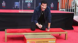 Lionel Richie membubuhkan tanda tangan sebelum mengabadikan cetak tangan dan kakinya di TCL Chinese Theatre, Hollywood, Rabu (7/3). Richie menerima berbagai penghargaan internasional dan penghargaan dari sejumlah negara. (Tommaso Boddi/Getty Images/AFP)