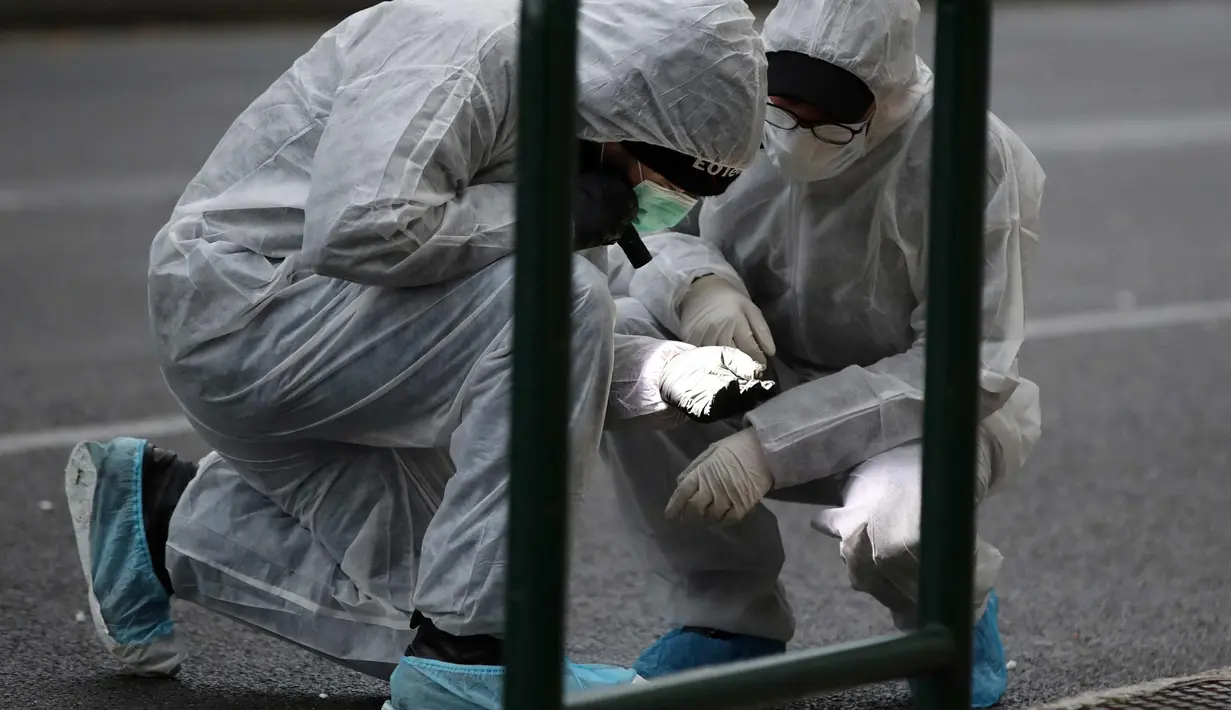 Petugas kepolisian mencari barang bukti usai ledakan bom di Pengadilan Banding di Athena, Jumat, (22/12). Sebuah ledakan dahsyat telah merusak kompleks pengadilan di pusat kota Athena. (AP Photo / Thanassis Stavrakis)