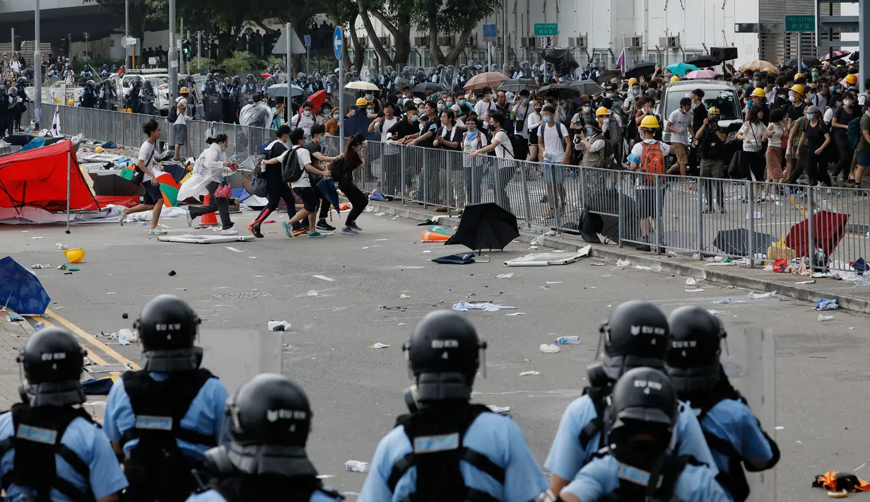 Polusi anti huru hara berusaha membubarkan demonstran di luar gedung Dewan Legislatif, Hong Kong, Rabu (12/6/2019). Bentrok diawali ketika para pengunjuk rasa merangsek melewati garis polisi dan memaksa masuk ke gedung Dewan Legislatif. (AP Photo/Kin Cheung)