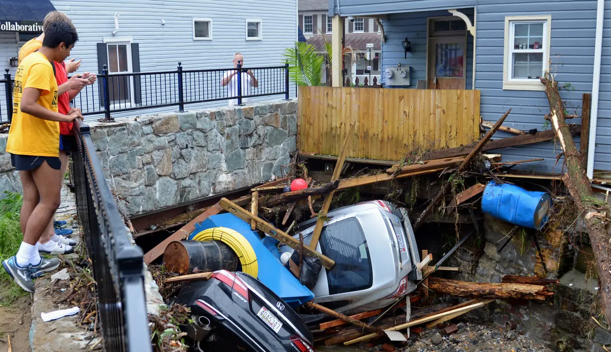 Warga berkumpul untuk melihat sejumlah mobil yang tersangkut di sebuah jembatan di Ellicott City, Maryland, Amerika Serikat, Senin (28/5). Banjir bandang Maryland diakibatkan meluapnya Sungai Patapsco. (AP Photo/David McFadden)