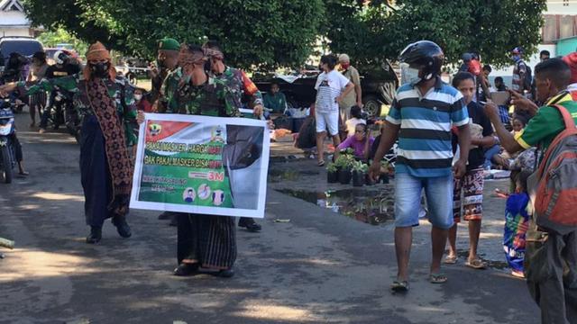 Anggota Kodim1603 Sikka mengenakan busana adat Sikka dan memberikan edukasi serta sosialisasi penerapan prokes  kepada warga pengguna pasar Alok, Maumere, Kabupaten Sikka, NTT. (Liputan6.com/ Dionsius Wilibardus)